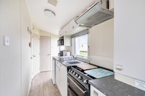 Cocina funcional con estufa, pileta y microondas.