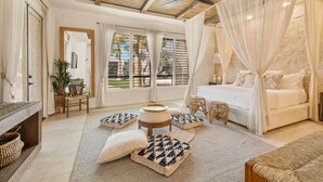 A spacious bedroom with a large bed, a ceiling fan, and a view of the outdoors through large windows. - Luxe Villa Tulum in Indio (Indio)