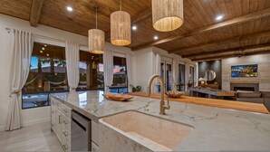 A modern kitchen with a large island, stainless steel appliances, and pendant lighting. - Luxe Villa Tulum in Indio (Indio)