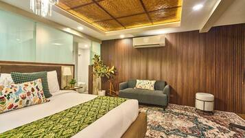 A hotel room with a bed, a sofa, a small table, and a decorative plant.