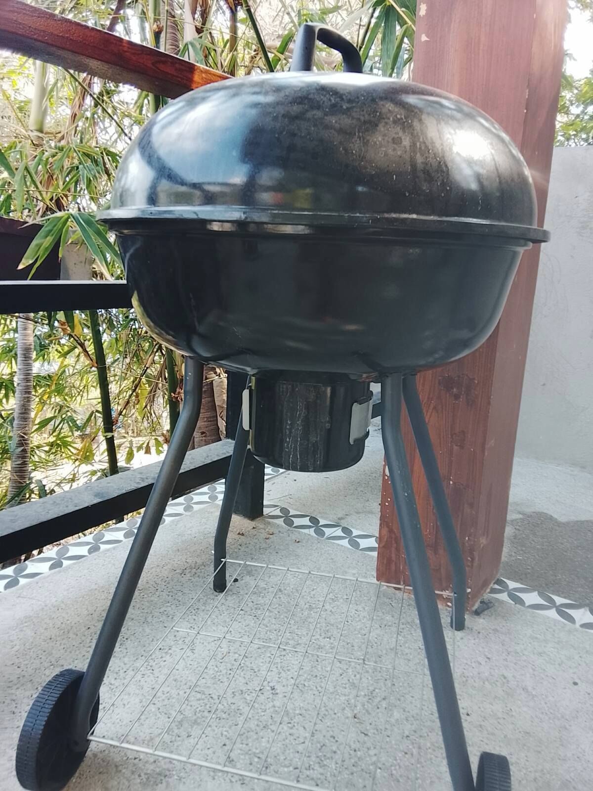 Un barbecue sur un balcon doté d’un sol carrelé et d’une rambarde en bois.