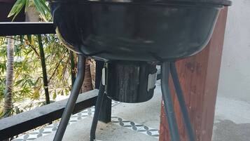 Un barbecue sur un balcon doté d’un sol carrelé et d’une rambarde en bois.