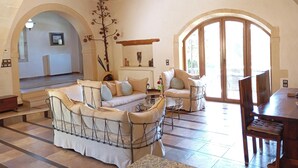 A spacious living room with a high ceiling, wooden beams, a large sofa, and a dining area.