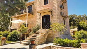 A stone building with a balcony, a staircase, and a door.