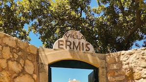 An entrance to Villa Ermis with stone walls and a clear view of the building beyond.
