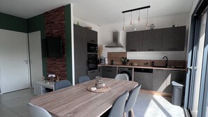 A modern kitchen with dark cabinets, a wooden dining table, and grey chairs. - Villa Lillecorsa in porto vecchio (Lecci)