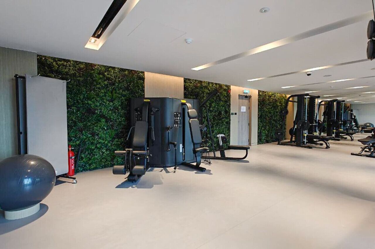 Een sportschool met diverse fitnessapparaten, een televisie aan de muur en een brandblusser.