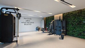 Ein modernes Fitnessstudio mit Trainingsgeräten, einem motivierenden Spruch an der Wand und einer grünen Wand.
