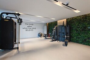 A modern gym with exercise equipment, a motivational quote on the wall, and a green wall. - Trendy Loft Studio in Oxford Terrace JVC (Dubai)