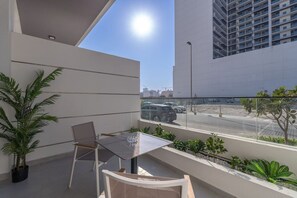 Un balcon avec une table et des chaises, des plantes en pot et une vue sur une rue et des immeubles.