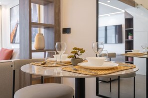 A modern dining area with round tables, clear glassware, and a bonsai tree centerpiece. - Trendy Loft Studio in Oxford Terrace JVC (Dubai)