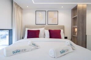 Une chambre d’hôtel avec un lit, deux oreillers, une fenêtre et des œuvres d’art accrochées au mur.