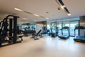 A modern gym with various exercise equipment, large windows, and a clean, spacious layout.