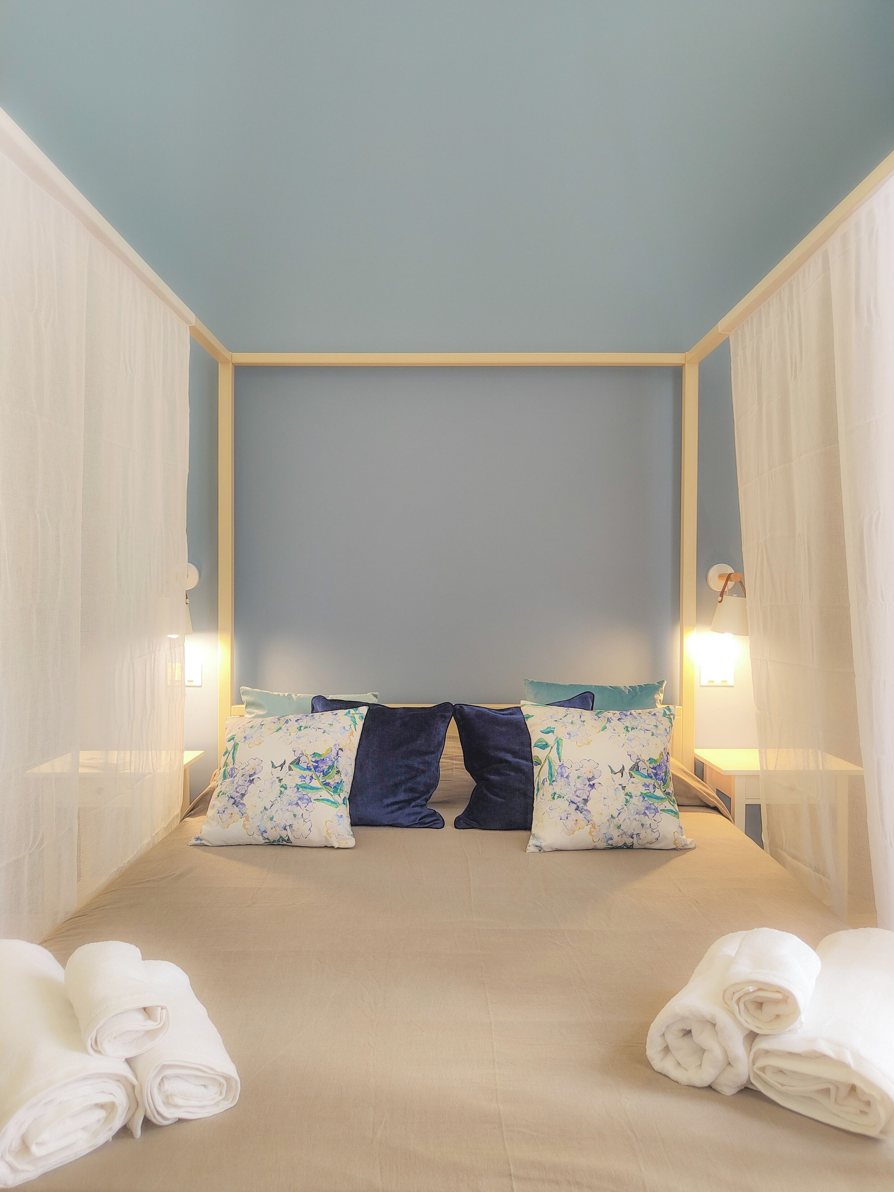A bedroom with a bed, pillows, a nightstand, and a lamp.