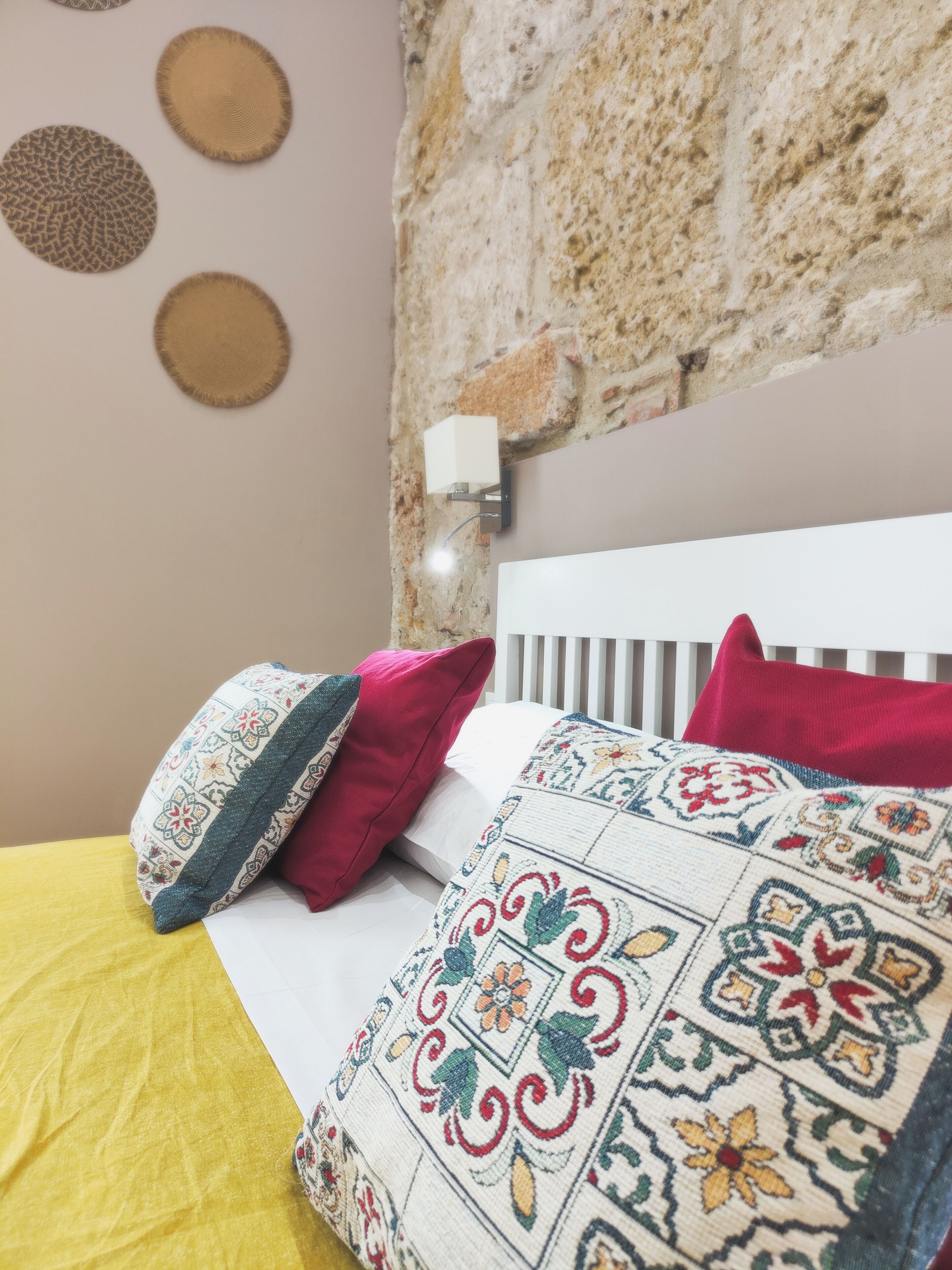 Een bed met een gele sprei, twee kussens en een gebogen deken.