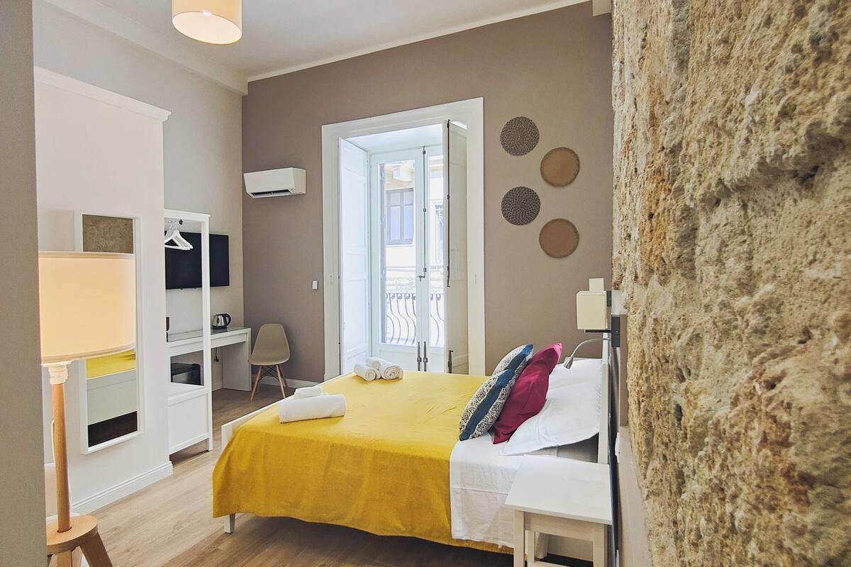 Um quarto com uma cama, uma escrivaninha, uma cadeira e um guarda-roupa.