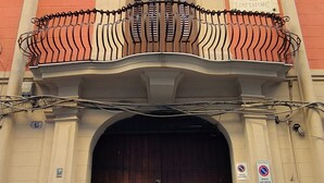 A building facade with a large wooden door, a balcony with wrought iron railings, and a plaque with historical information. - Dimora Carella (Palermo)