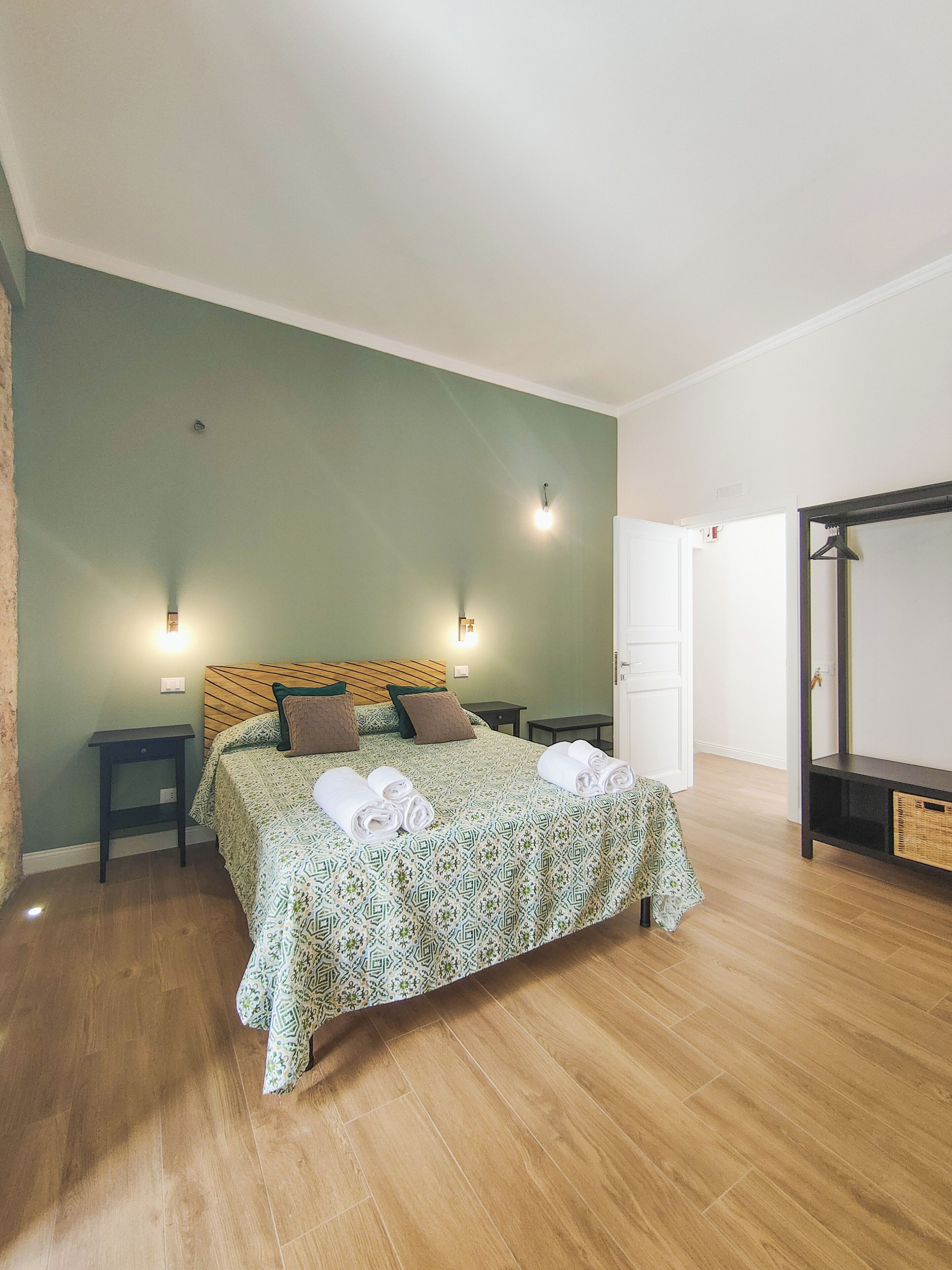 A bedroom with a bed, two bedside tables, a hanging light fixture, and a wardrobe.