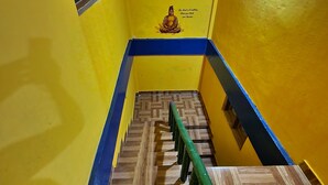 A staircase with wooden steps and a green handrail, leading to a room with a yellow wall and a small window. - Akash Deep Bhawan By GRB (Bokakhat)