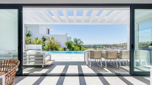 A modern outdoor patio with a pool, white furniture, and a view of a coastal landscape. - Marbella Holiday Villa with Sea Views & Heated Pool, Gym (AN)