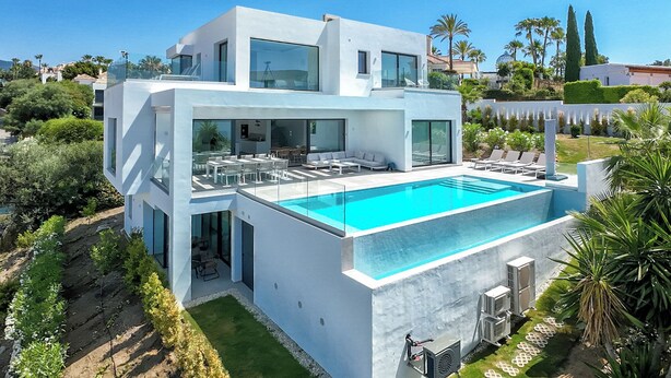 A modern two-story house with a large swimming pool, outdoor seating, and a well-maintained garden. - Marbella Holiday Villa with Sea Views & Heated Pool, Gym (AN)