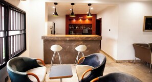 A bar area with a counter, two stools, and a table.