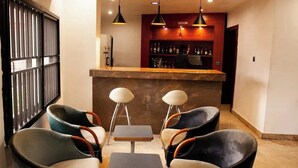 A bar area with two tables and four chairs, a red wall with a bar counter, and an air conditioning unit on the wall. - Genesis Castle (Port Harcourt)
