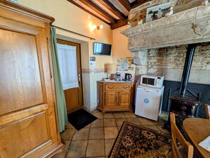 A kitchen with wooden cabinets, a microwave, a stove, and a television above the counter. - Charming rooms with enclosed park and secure parking (Choye)