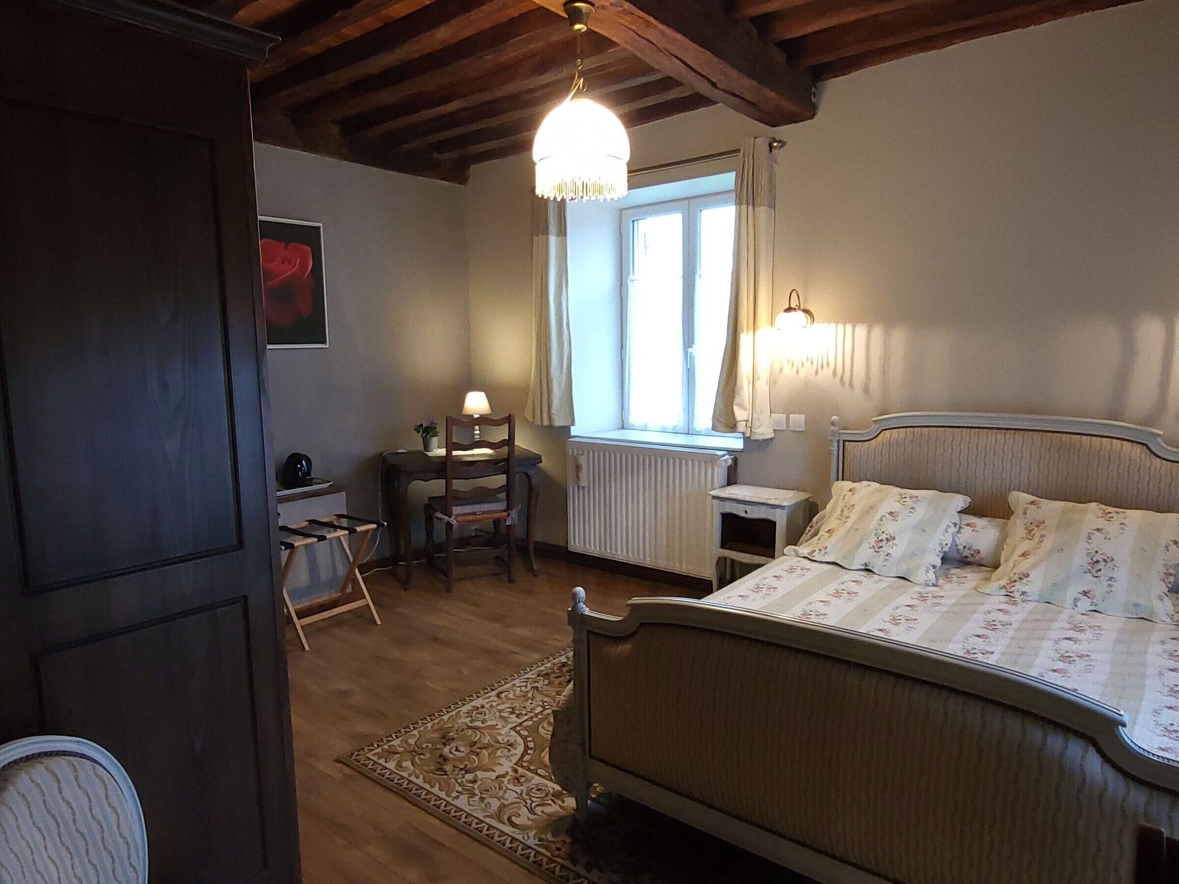 A bedroom with a bed, a chair, a desk, a radiator, and a window.