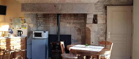 Una cocina rústica con chimenea de piedra, muebles de madera y piso de baldosas.