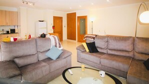 A living room with two sofas, a coffee table, and a kitchen area in the background. - Spacieux Appart à 200m de la Plage de Roses - Terrasse BBQ, Parking Gratuit, 8 pers (Roses)