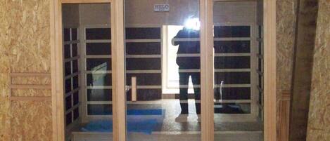 Una habitación con estructura de madera, una puerta de vidrio, un letrero pequeño y una persona parada en el umbral.