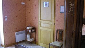 A room with a wooden door, a small table with books and a kettle, a radiator, and a cabinet. - Countryside Retreat with Fitness Space in La Berthenoux (La Berthenoux)