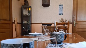 A dining table set with plates, glasses, and a pitcher. There is a cabinet with dishes and a wall-mounted sign. - Countryside Retreat with Fitness Space in La Berthenoux (La Berthenoux)