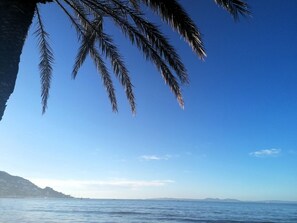 Cielo azul despejado con mar tranquilo y tierra a lo lejos.