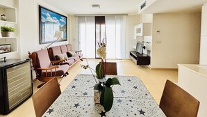Een moderne woonkamer met een bank, televisie, eettafel en decoratieve planten.