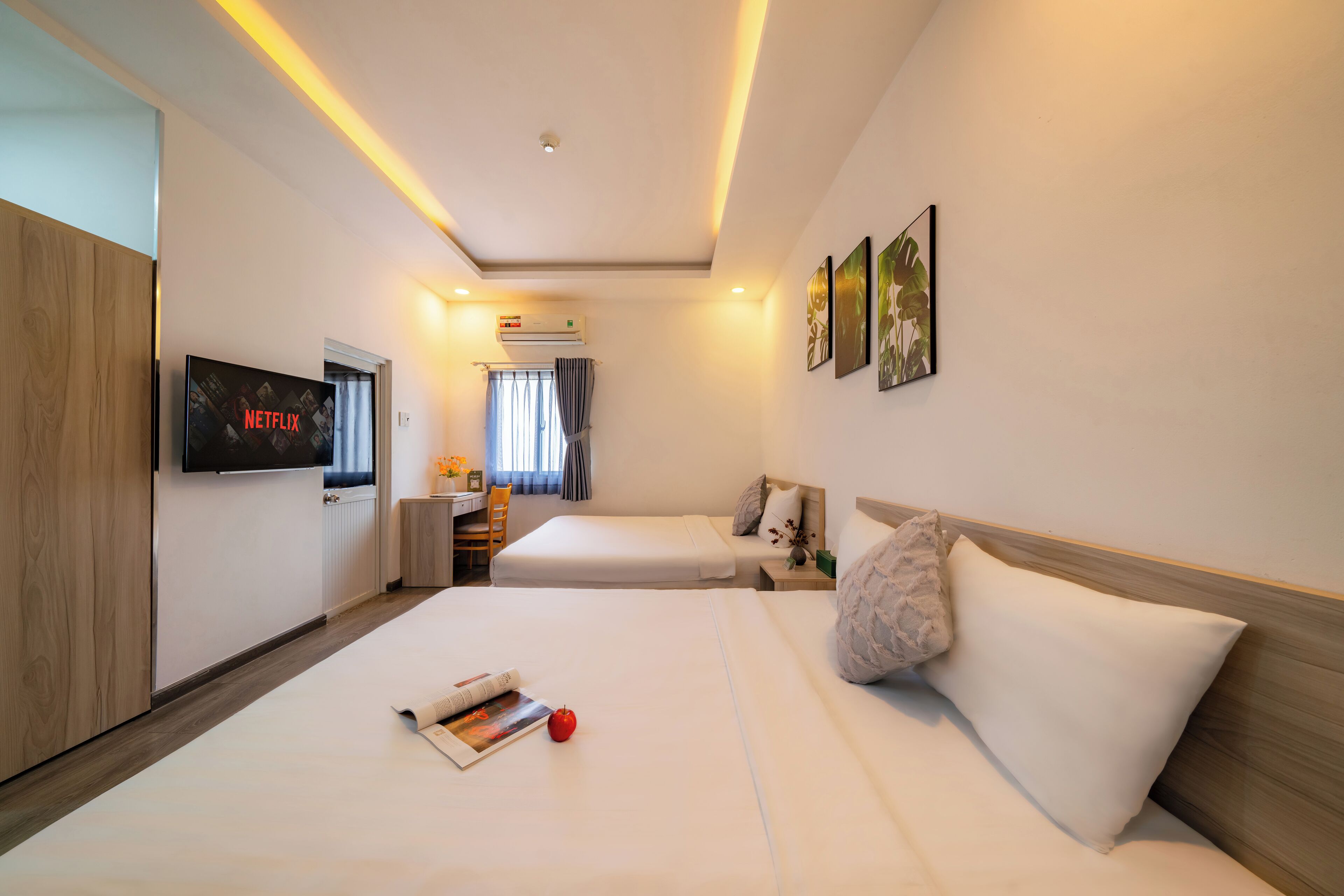Una camera d'albergo con un letto, comodino, televisore e un'opera d'arte appesa al muro.