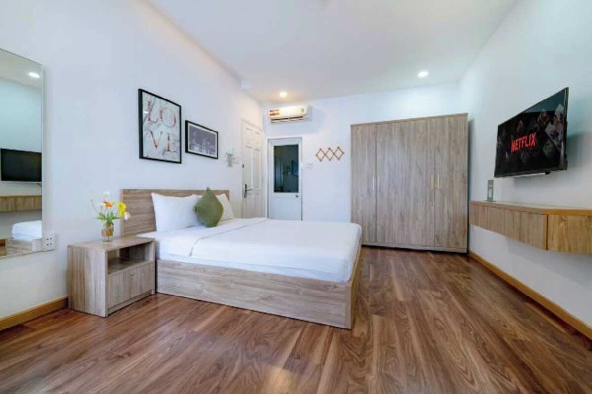 A modern bedroom with a wooden bed, a wardrobe, a TV, and a wall-mounted air conditioner.