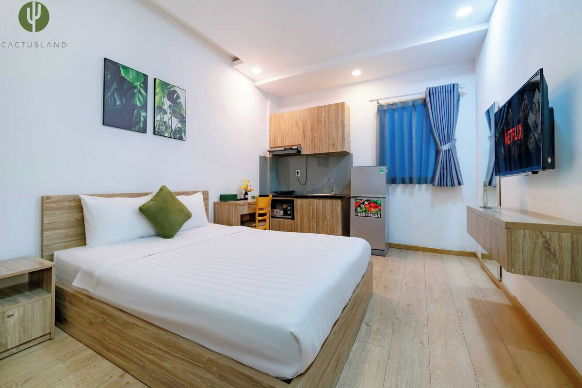 Une chambre d’hôtel moderne dotée d’un grand lit, d’une kitchenette, d’une télévision et d’œuvres d’art accrochées aux murs.