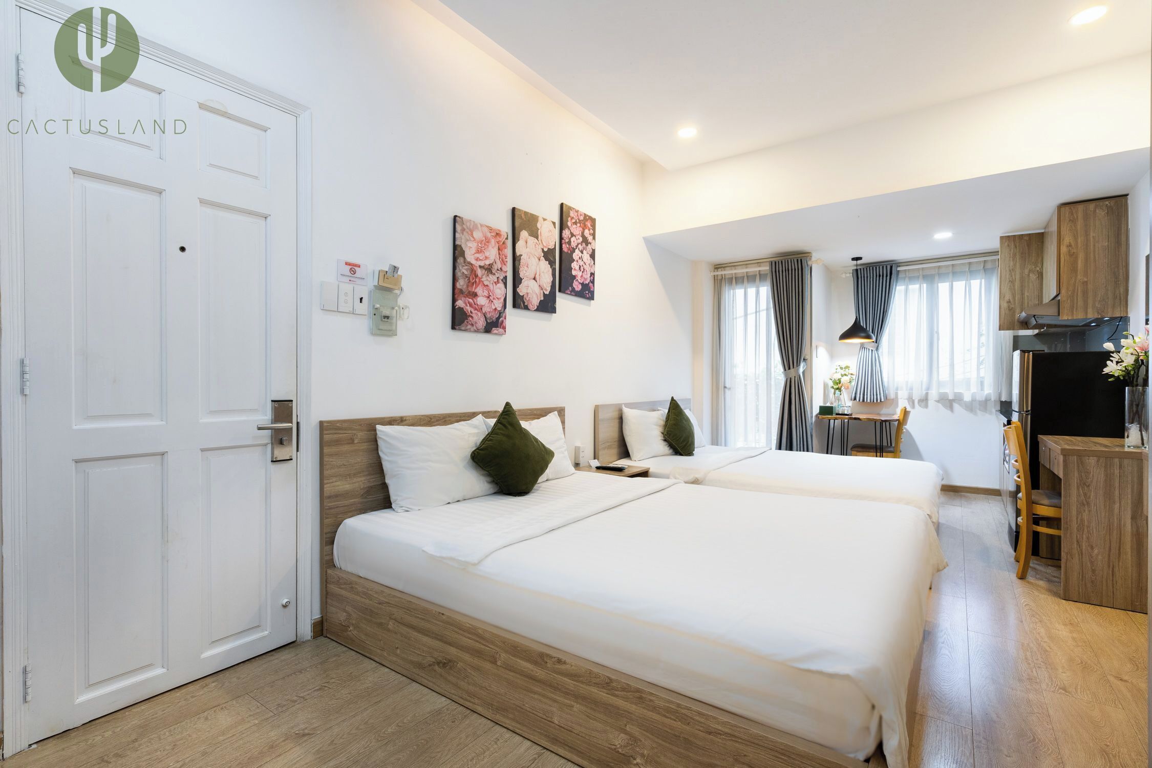 Habitación de hotel con dos camas, un escritorio, una silla, un televisor y una ventana con cortinas.