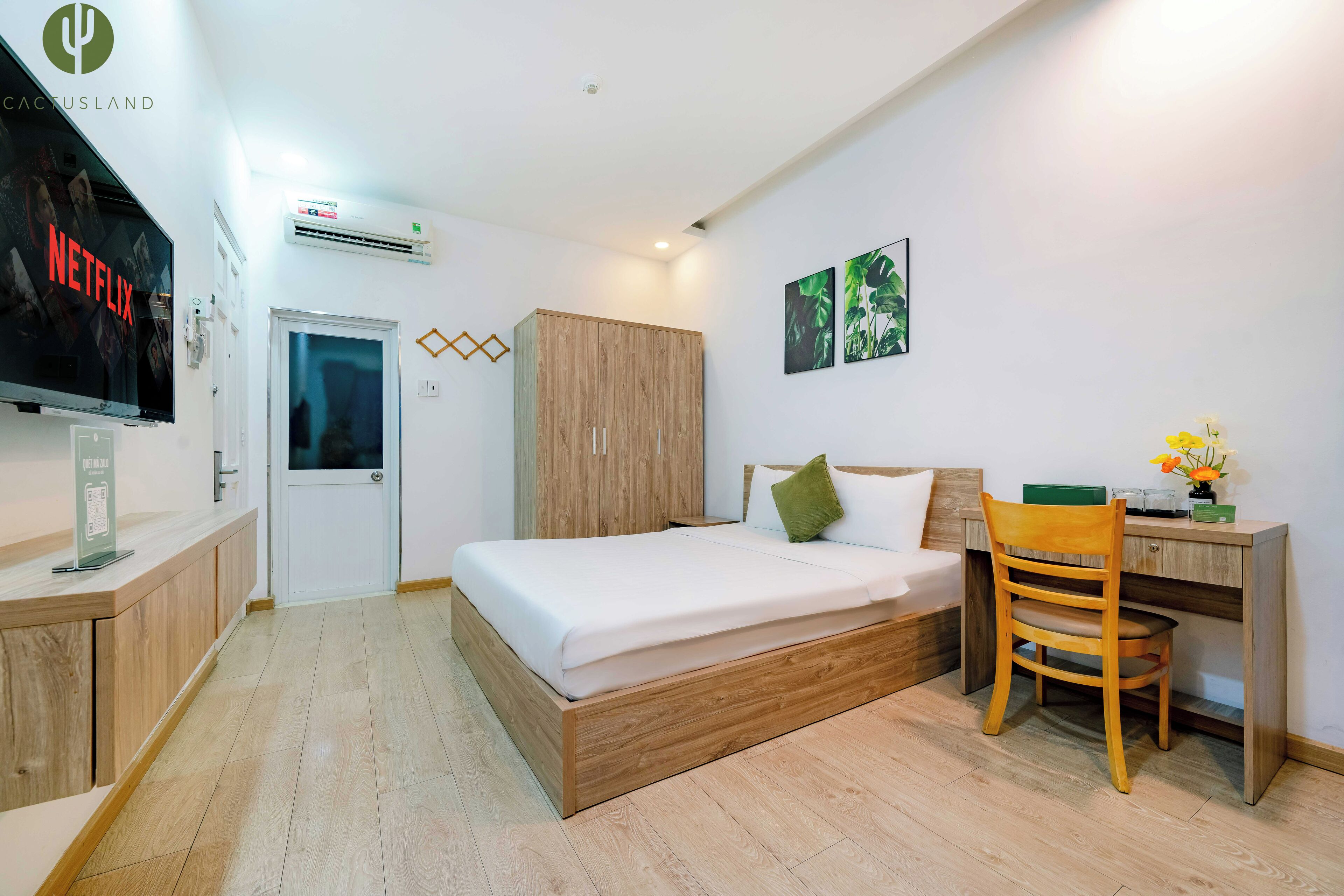 Une chambre moderne avec un lit en bois, un bureau et un téléviseur affichant le logo de Netflix.
