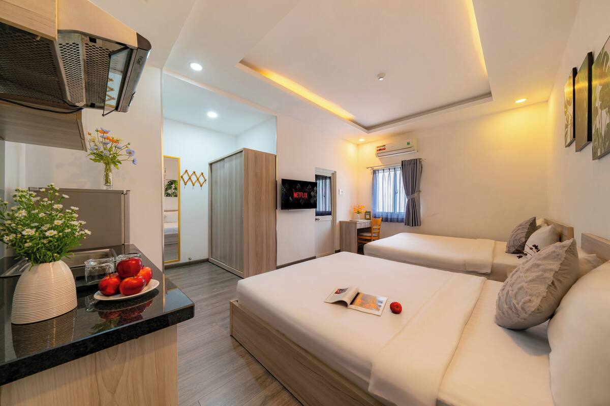 Une chambre d’hôtel moderne équipée d’une kitchenette, d’une télévision, de deux lits et d’une salle de bain.