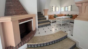 A spacious living area with a fireplace, a sofa set, and a staircase with decorative tiles.