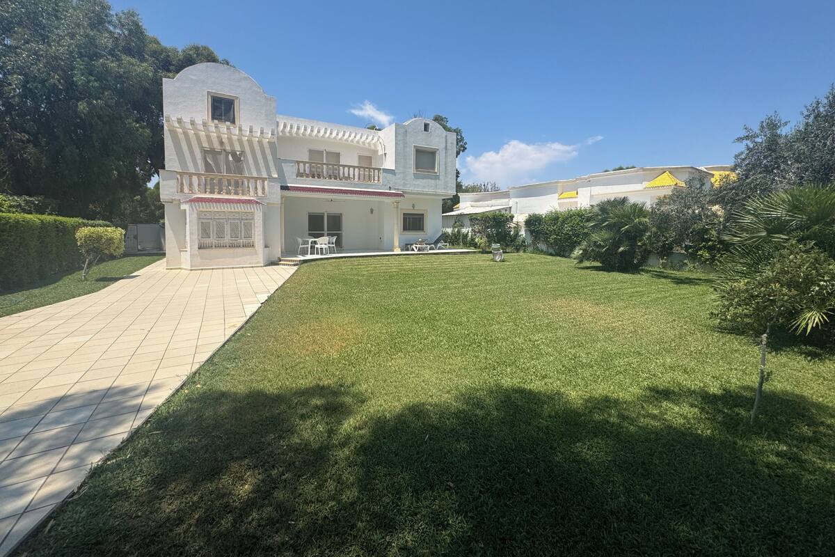 Una casa de dos pisos con un porche cubierto y un césped bien cuidado.