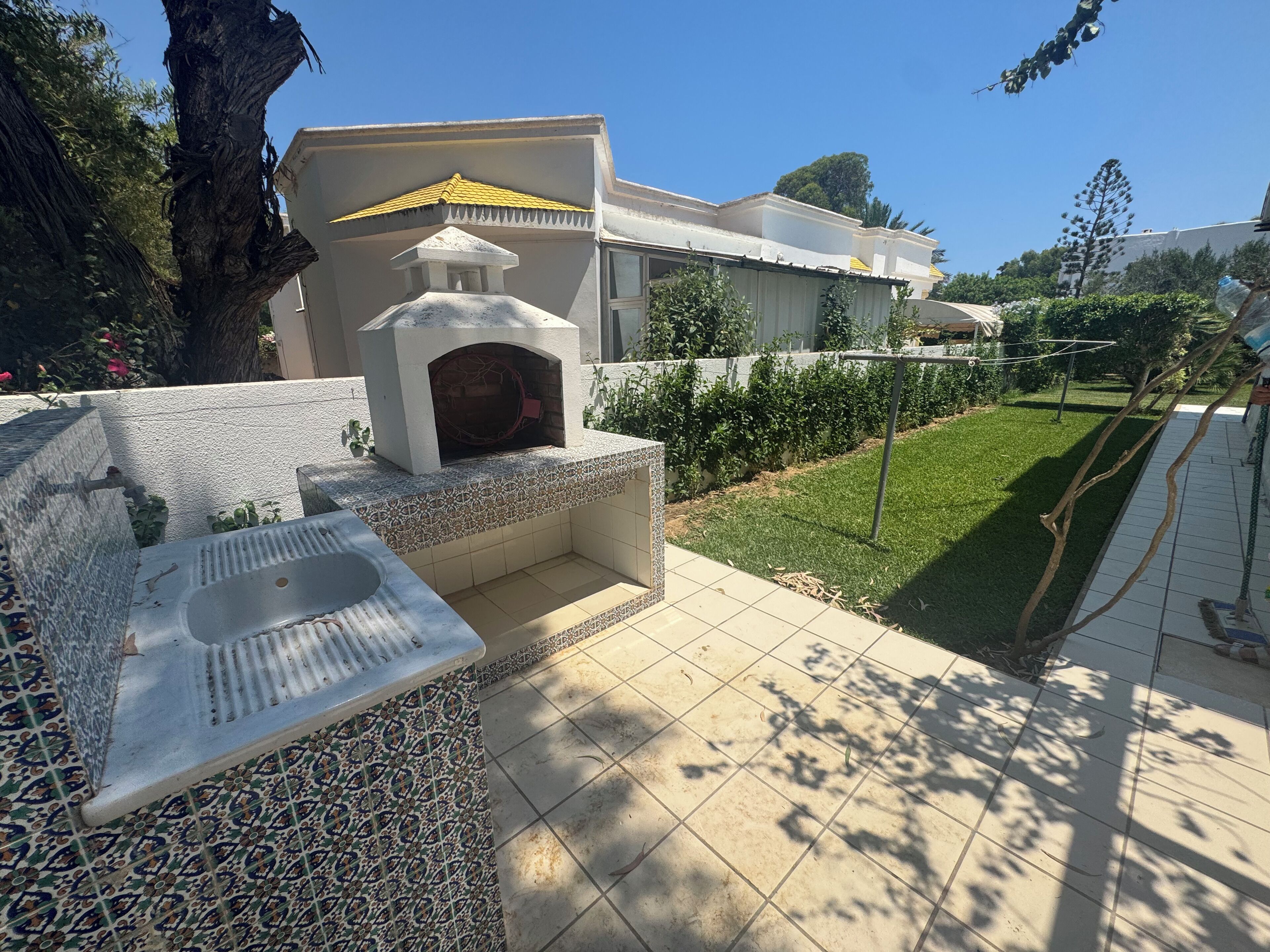 Un patio con un lavabo de piedra y una pequeña chimenea exterior.
