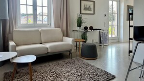 A modern living room with a sofa, a coffee table, a rug, and a dining area with a table and chairs. - Villa with balcony in the city center, elevator, luxury apartment on the Beletage (Bad Hall)