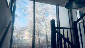 A room with large windows, a wooden staircase, and a view of trees and buildings outside. - Villa with balcony in the city center, elevator, luxury apartment on the Beletage (Bad Hall)