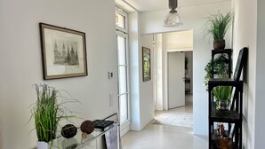 A hallway with a glass shelf holding plants and a framed picture, a hanging light fixture, and a door leading to another room. - Villa with balcony in the city center, elevator, luxury apartment on the Beletage (Bad Hall)