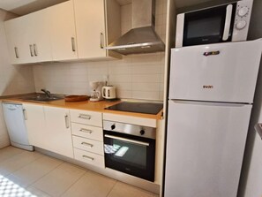 A compact kitchen with white cabinets, a built-in oven, a microwave, and a dishwasher. - A beautiful pool view apartment - AO1822LT (La Torre Golf Resort)