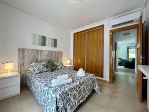 A bedroom with a bed, nightstands, a wardrobe, and a hallway leading to another room.